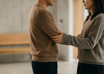Un homme et une femme se tenant face à face, se tenant doucement le bras dans une interaction intime et respectueuse.