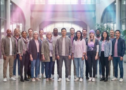 Un groupe diversifié de personnes debout ensemble dans un hall lumineux, avec des reflets subtils aux couleurs bisexuelles.
